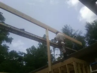 Carpenter setting a ridge beam over a new addition frame — Ice Dam Removal by Roofing Brothers in Farmland