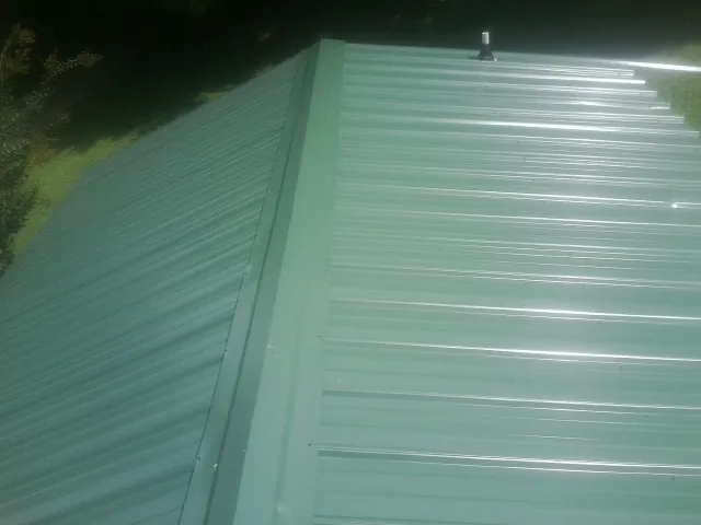 New green metal panels meeting at the ridge of a roof — Flat Roof Repair work by our crew in Farmland