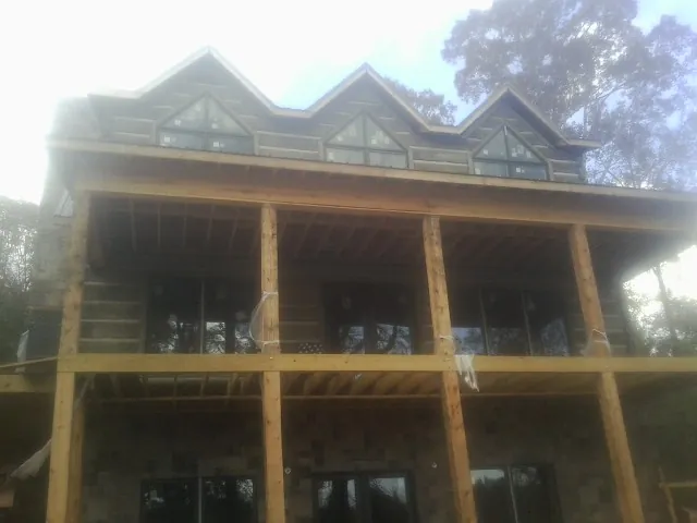 Dormers and porch framing on a large log home under construction — Roof Coating work by our crew in Farmland