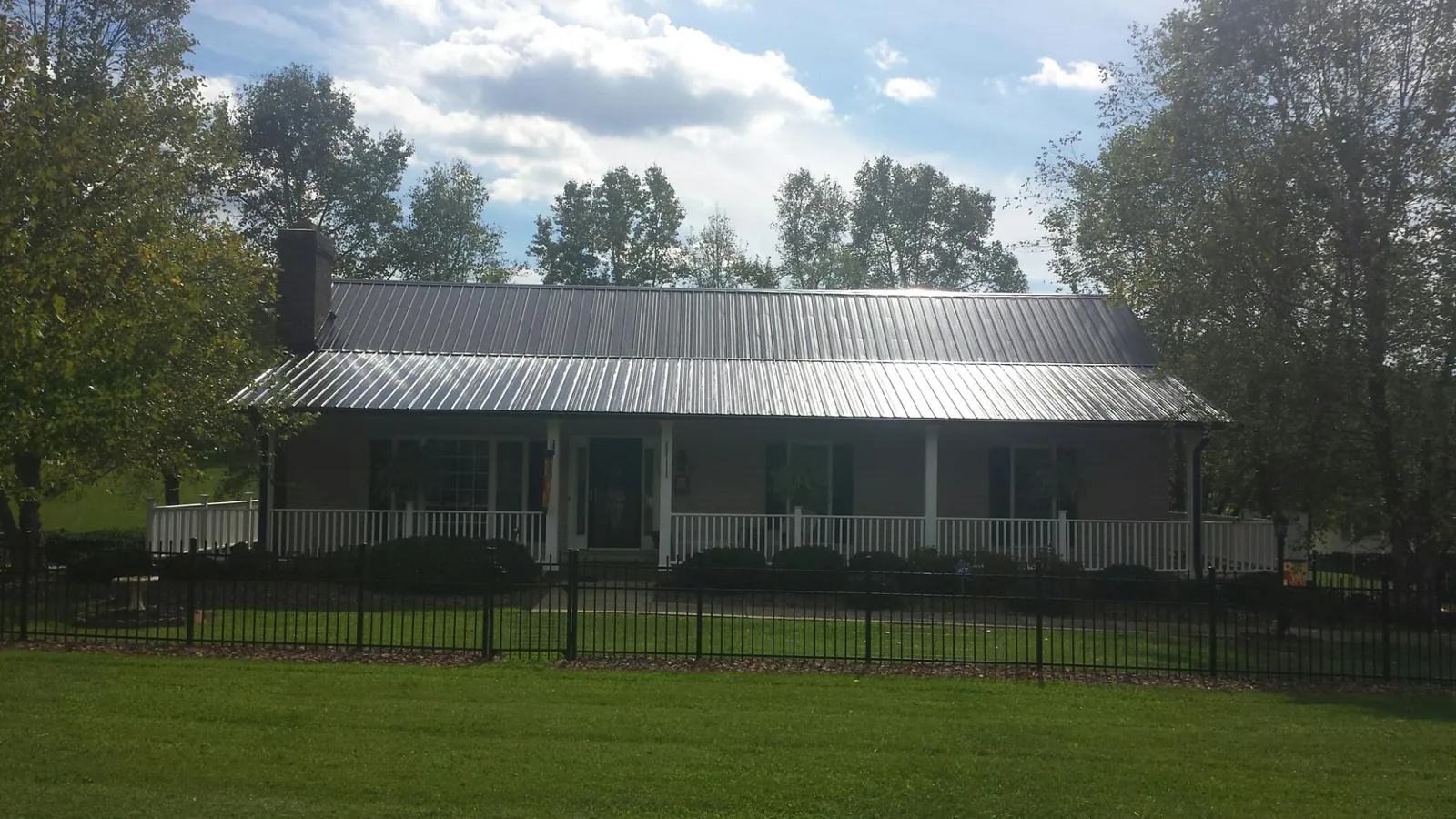 Gray metal roof on a brick ranch with a full width front porch — Gutter Guard Installation work by our crew in Farmland