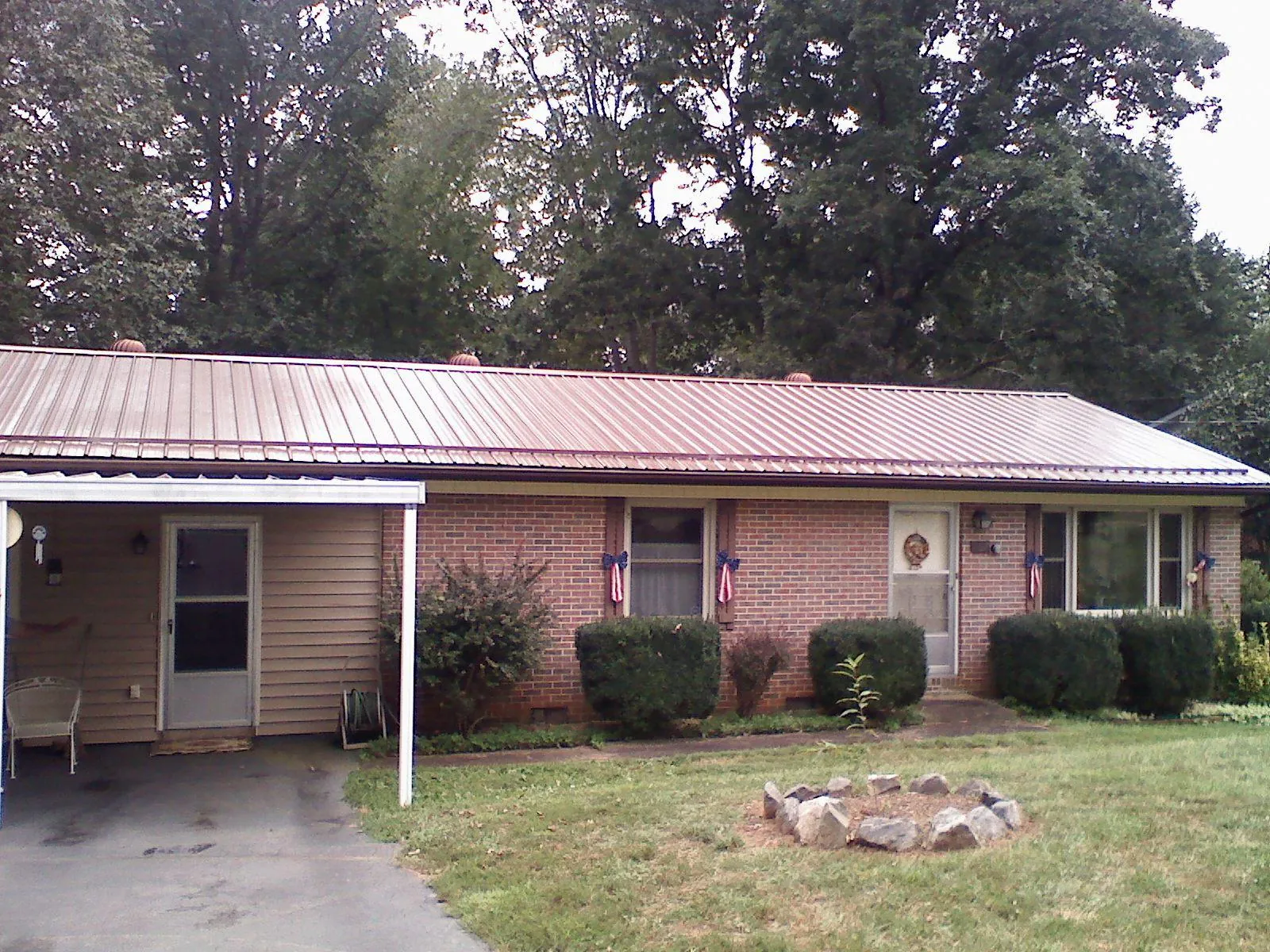 Bronze metal roof and carport on a brick ranch home — Roof Repair work by our crew in Farmland